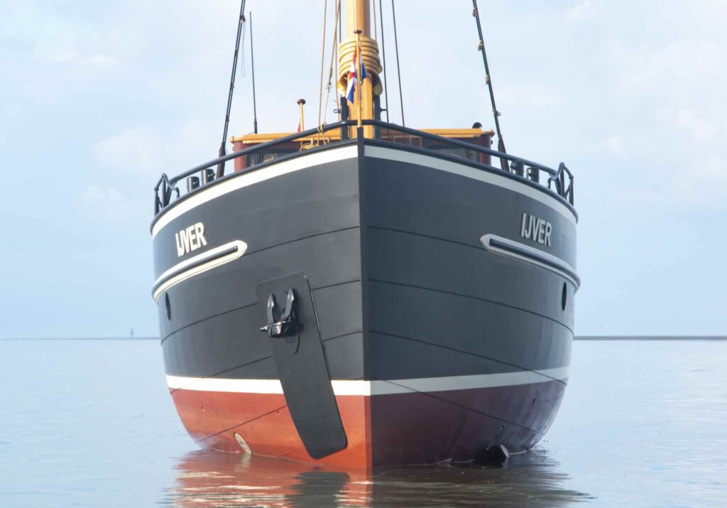 Het schip op het Wad, met de zwarte romp en de rode onderwaterzijde duidelijk in beeld.