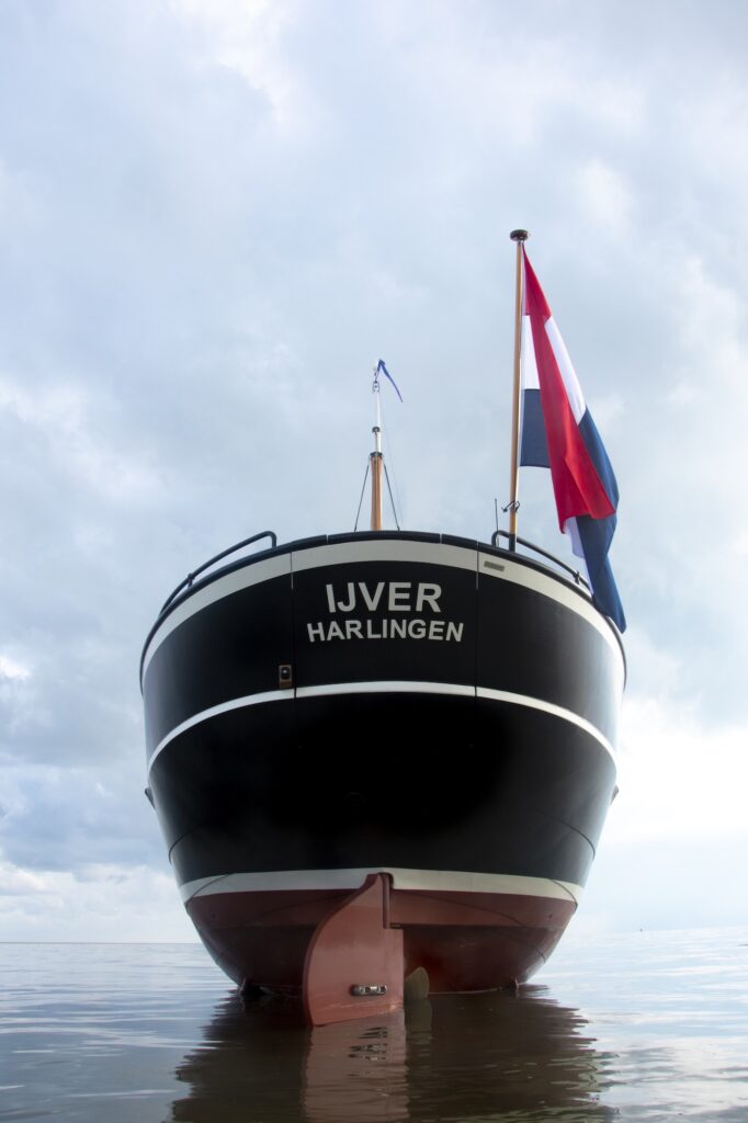 De IJver bij laagwater. De romp blijft rechtop staan op de drooggevallen bodem.
