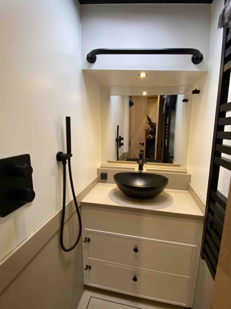 De badkamer met een ronde wastafel, spiegel en afzonderlijke douchevoorziening.