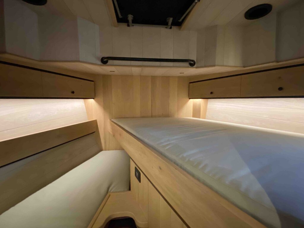 De slaapruimte in het voorschip, met een breed bed en bergruimte rondom.