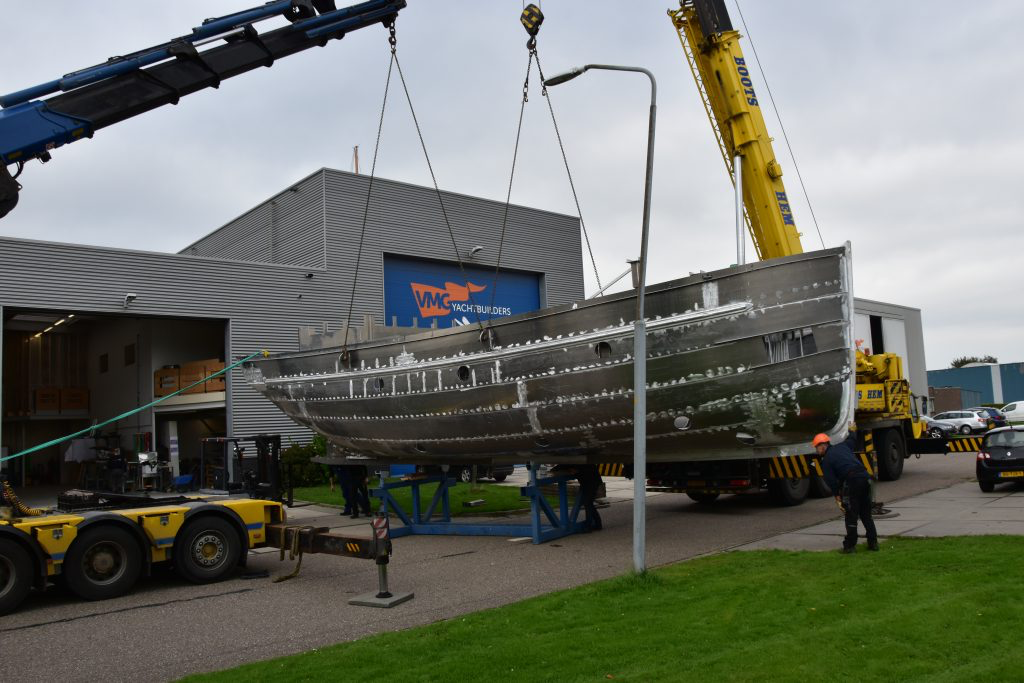 Het casco boven de transportwagen, met de hijsbanden langs de romp.