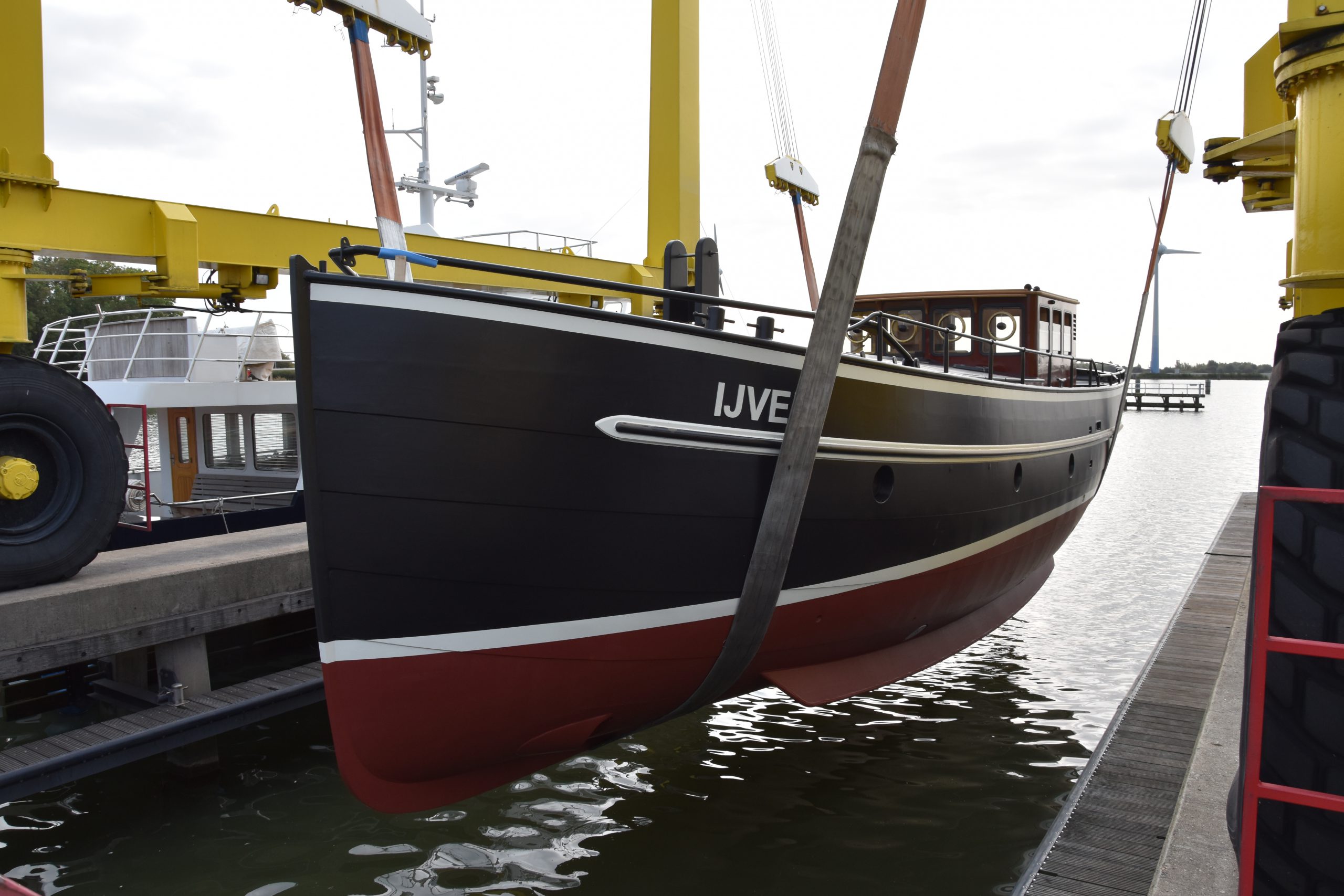 De IJver in de hijsbanden bij de werf, rond de doop en de afronding van het schip.