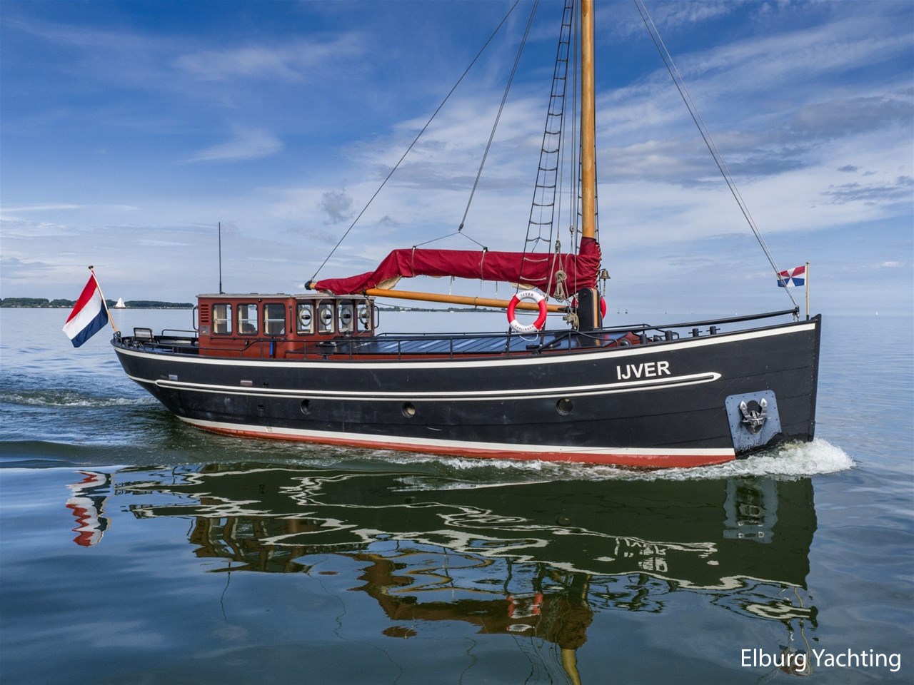 De IJver van opzij, met de rode zeilhoezen boven haar klassieke zwarte romp.
