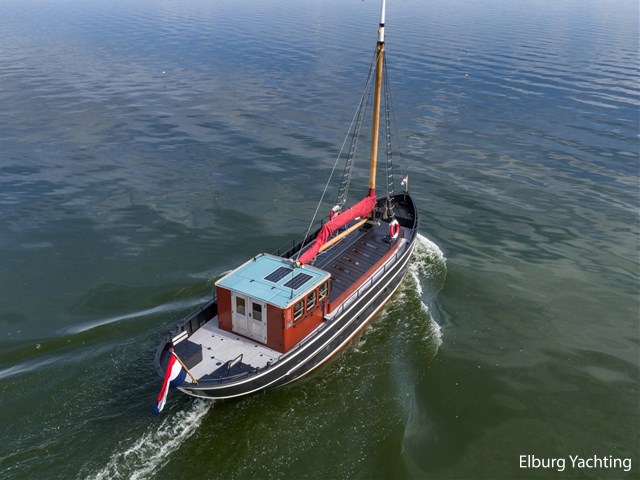 Een luchtfoto van De IJver laat de langgerekte romp en het open dek zien.